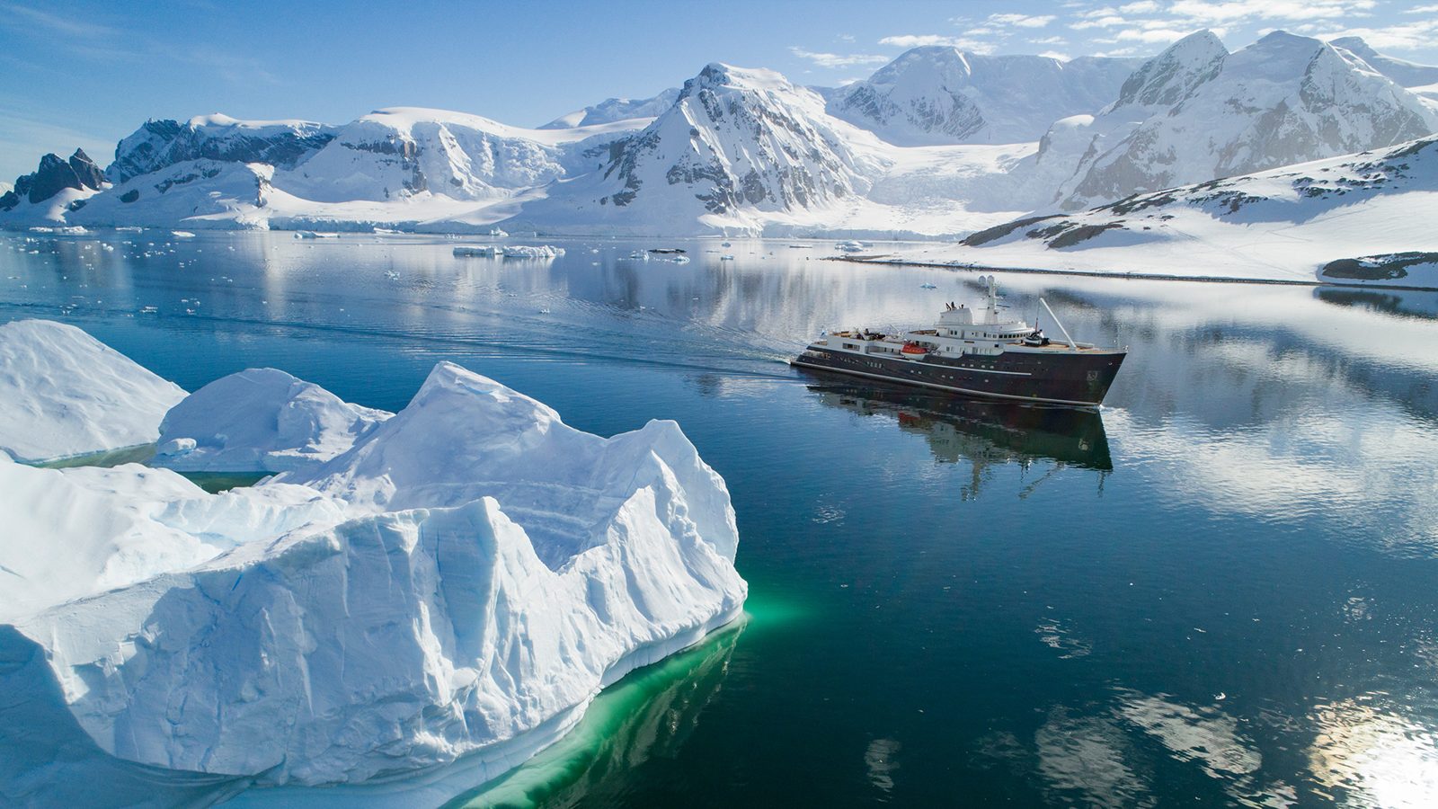 Expedition yacht surrounded by Antarctic mountains and ice